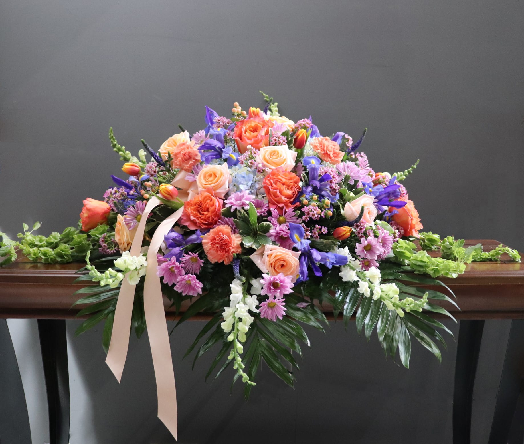 Large pastel floral spray with roses, carnations, and purple blooms