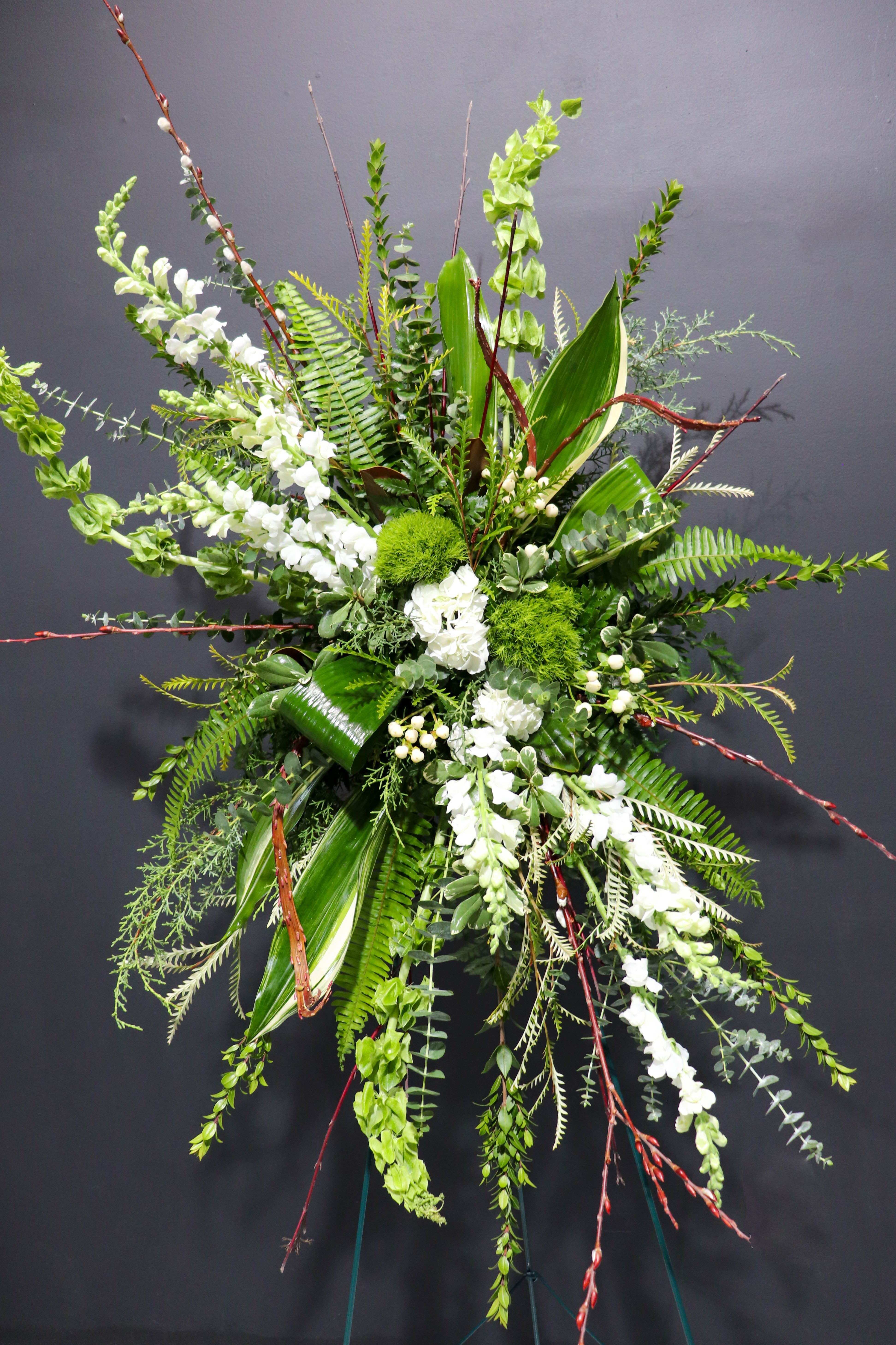 Tall floral spray with white blooms and lush green foliage