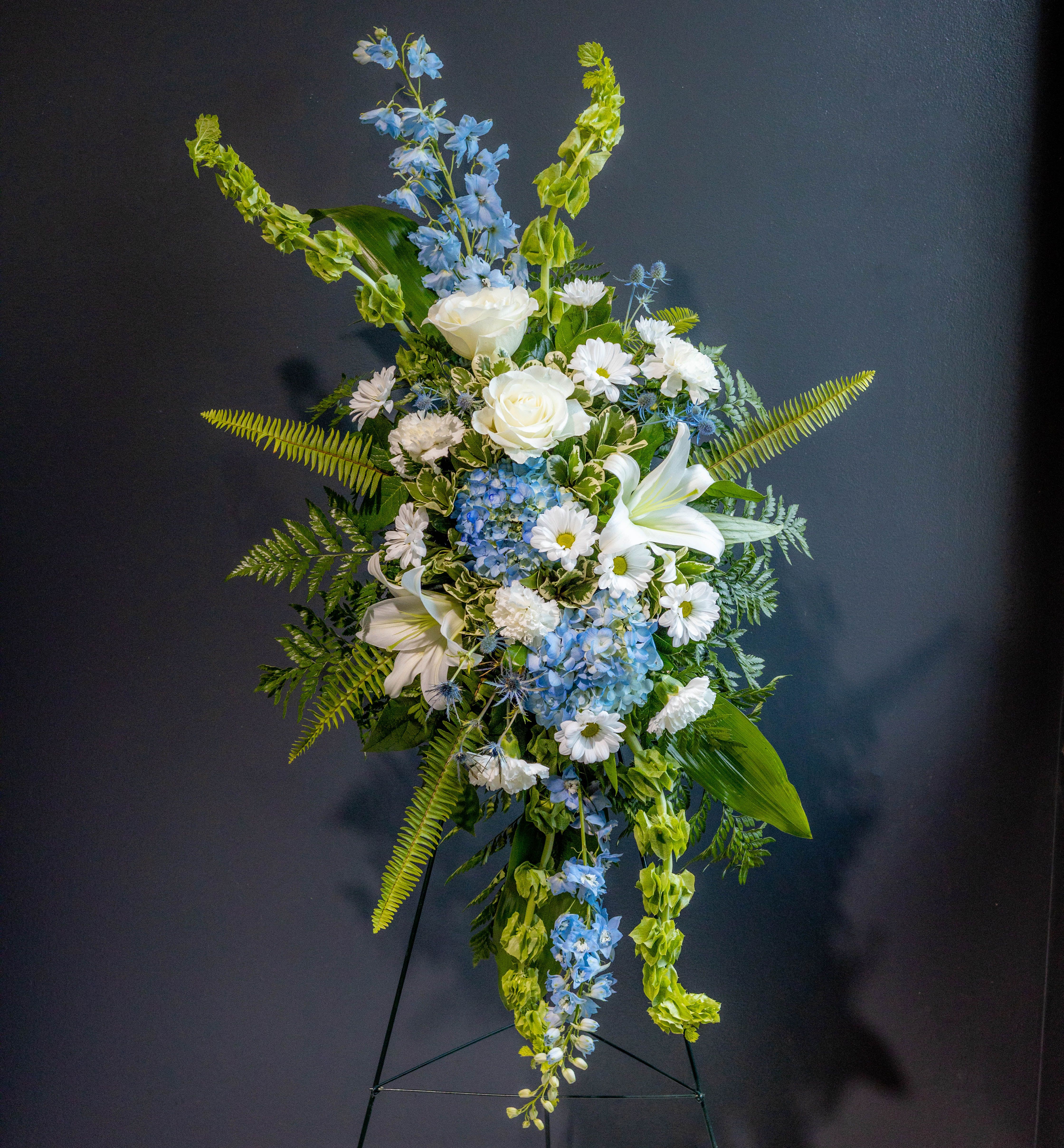 Blue + White Standing Spray (not as large as our standard standing spray) - A graceful tribute in shades of peace and remembrance, this Blue &amp; White Standing Spray conveys heartfelt condolences with quiet strength and elegance.