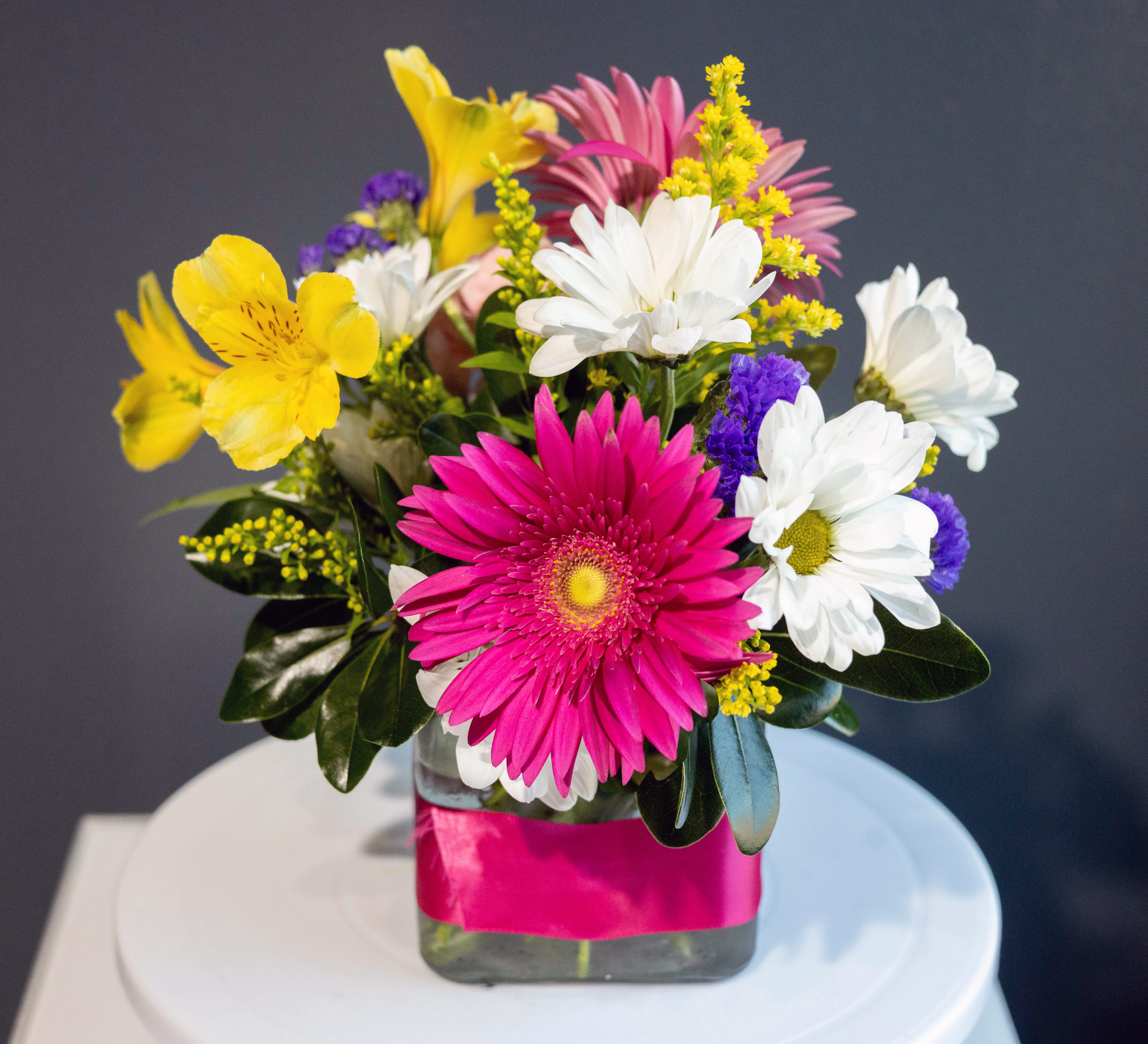 Mixed bouquet with pink, white, yellow, and purple flowers in a glass vase