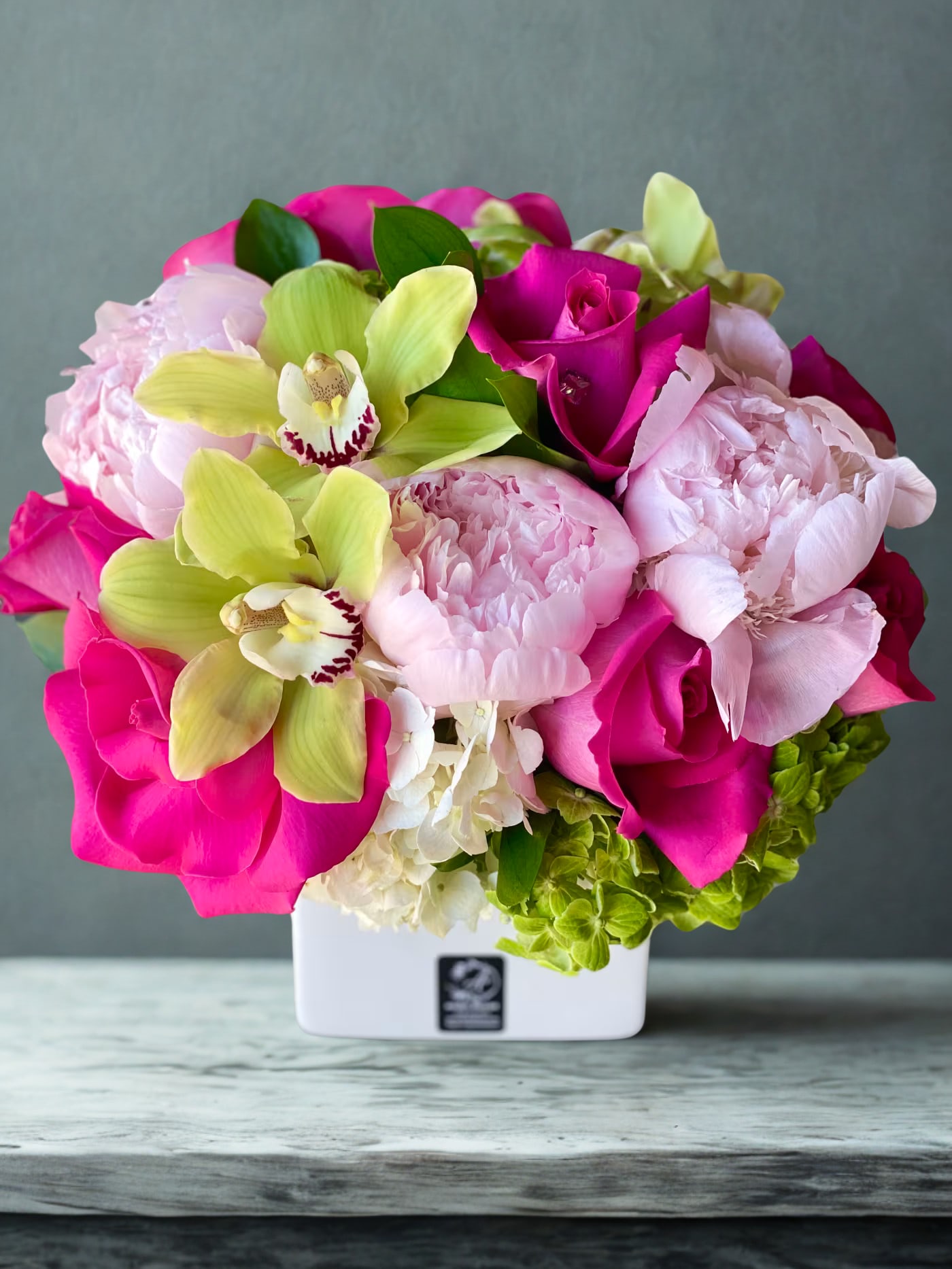 Pink and lime floral arrangement in a white square vase