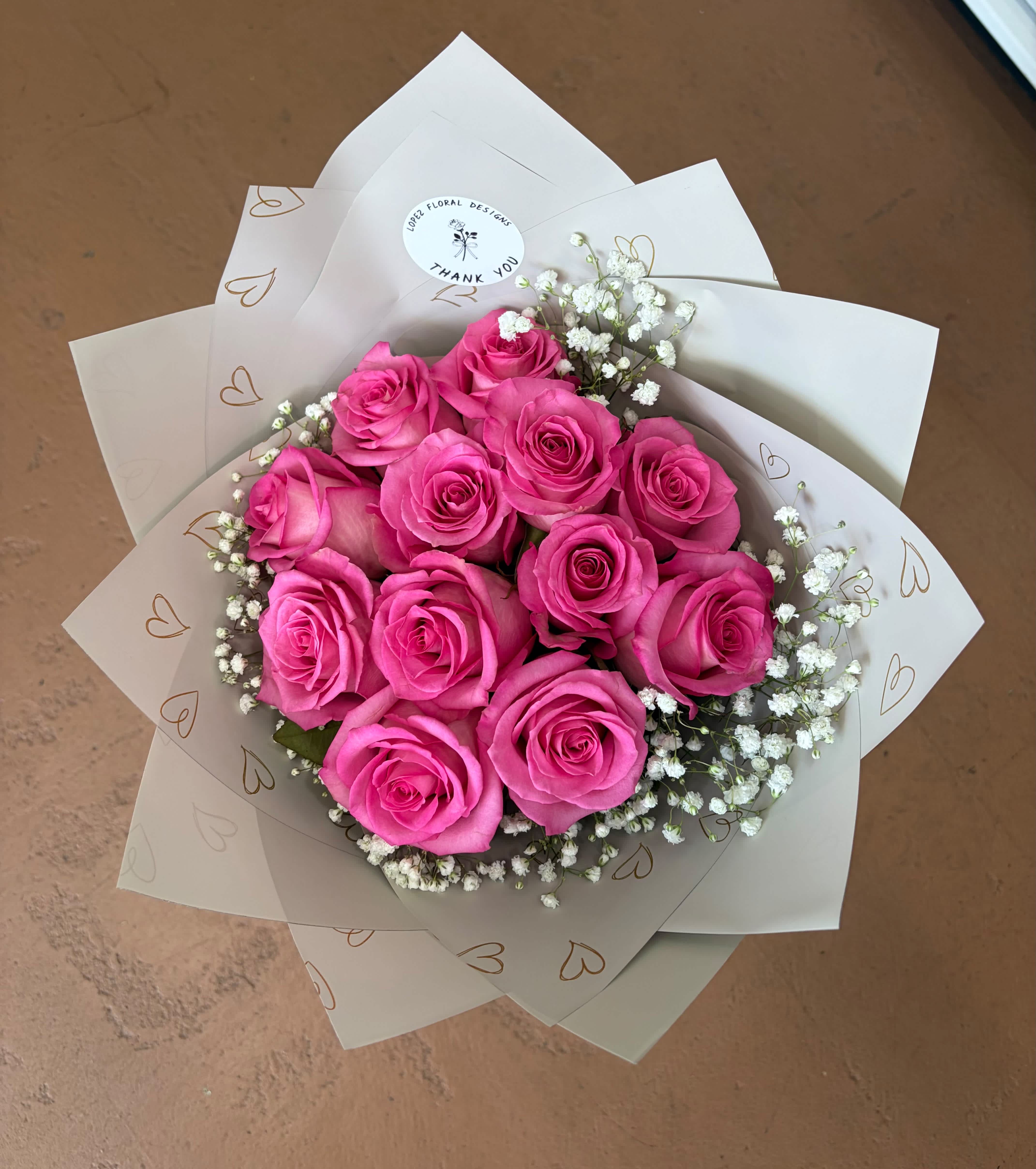 Bouquet of bright pink roses with white baby's breath in white wrap