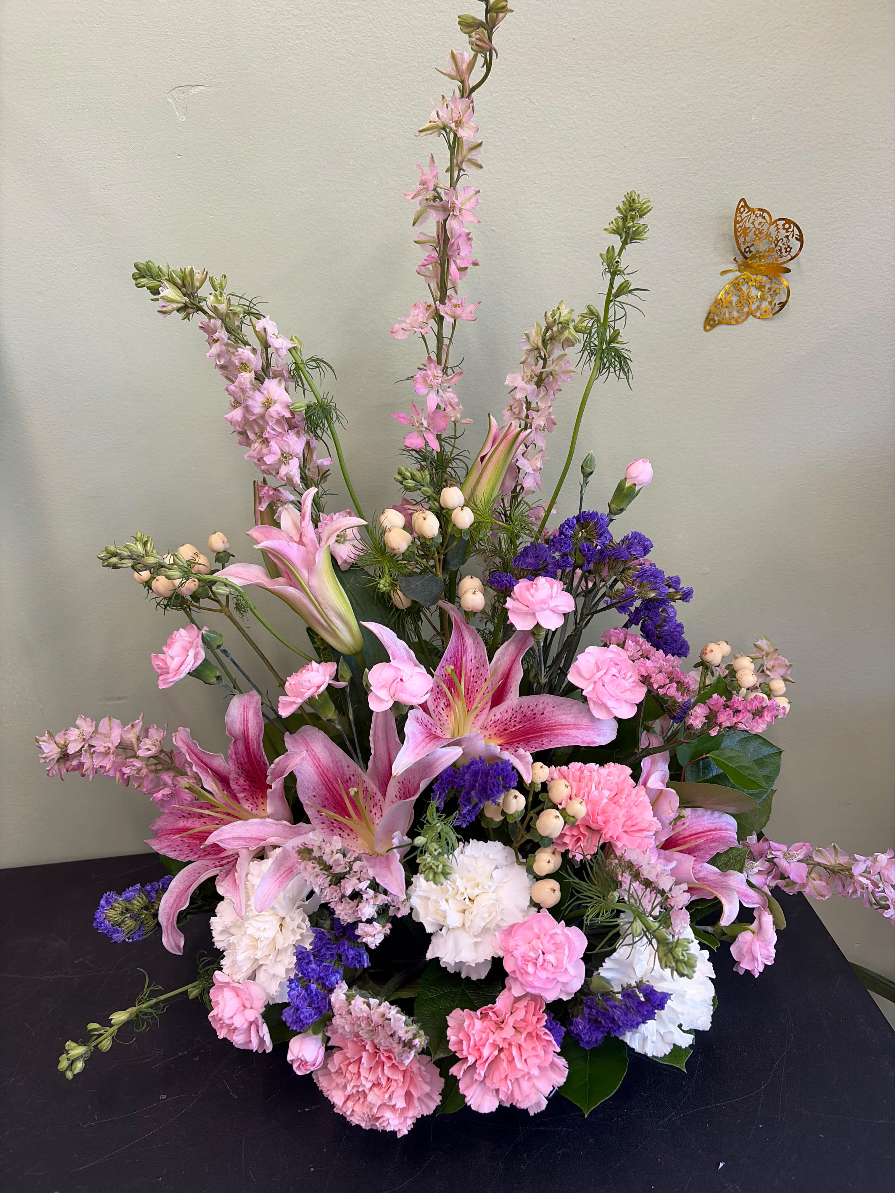 Pink lilies and carnations arranged with purple filler flowers