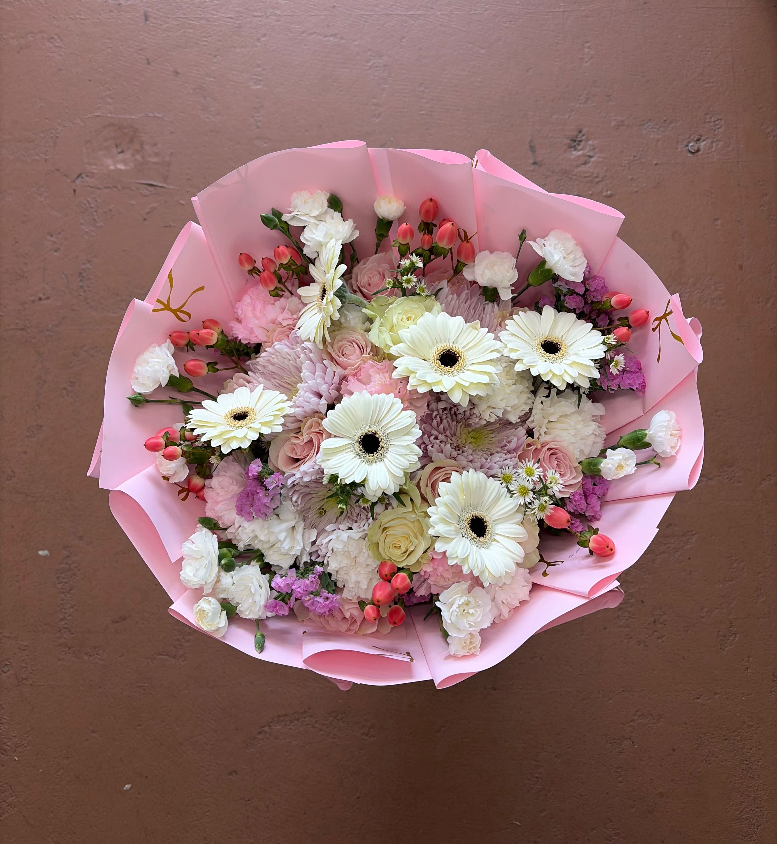 Pink-wrapped bouquet of white gerbera daisies and mixed pastel flowers