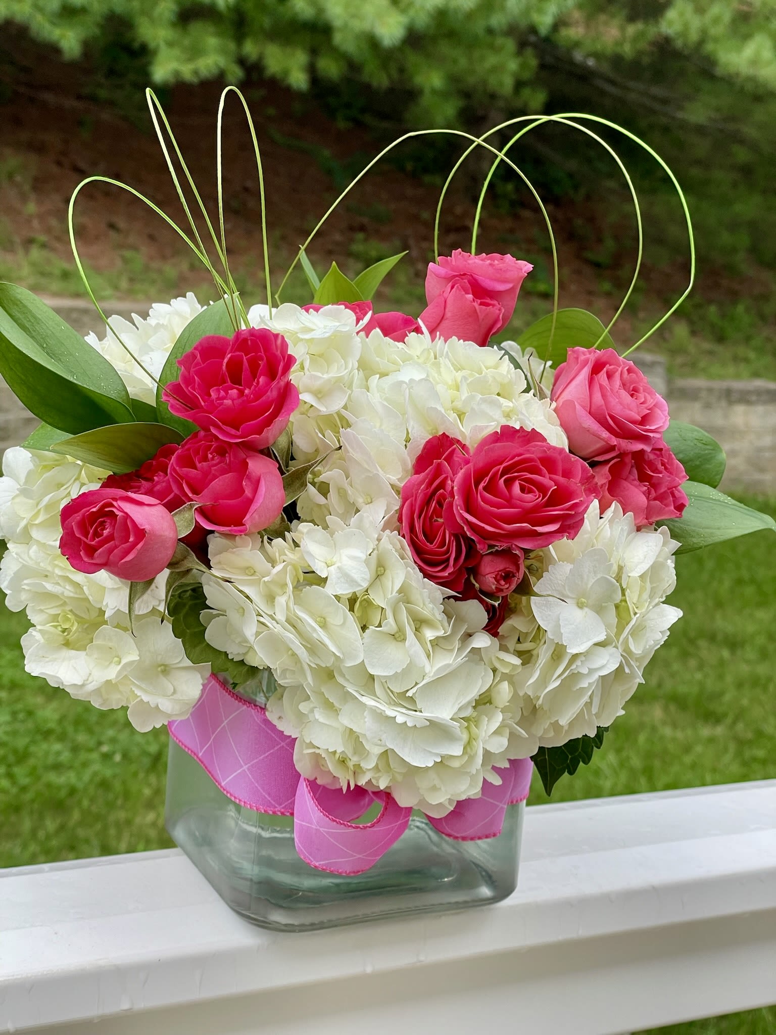 Pink roses and white hydrangeas in a glass vase with ribbon