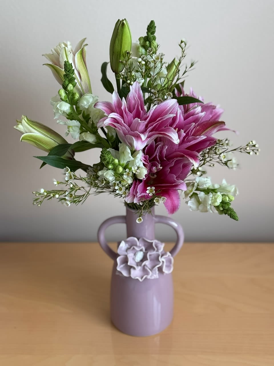 Pink lilies and white flowers in a lavender vase