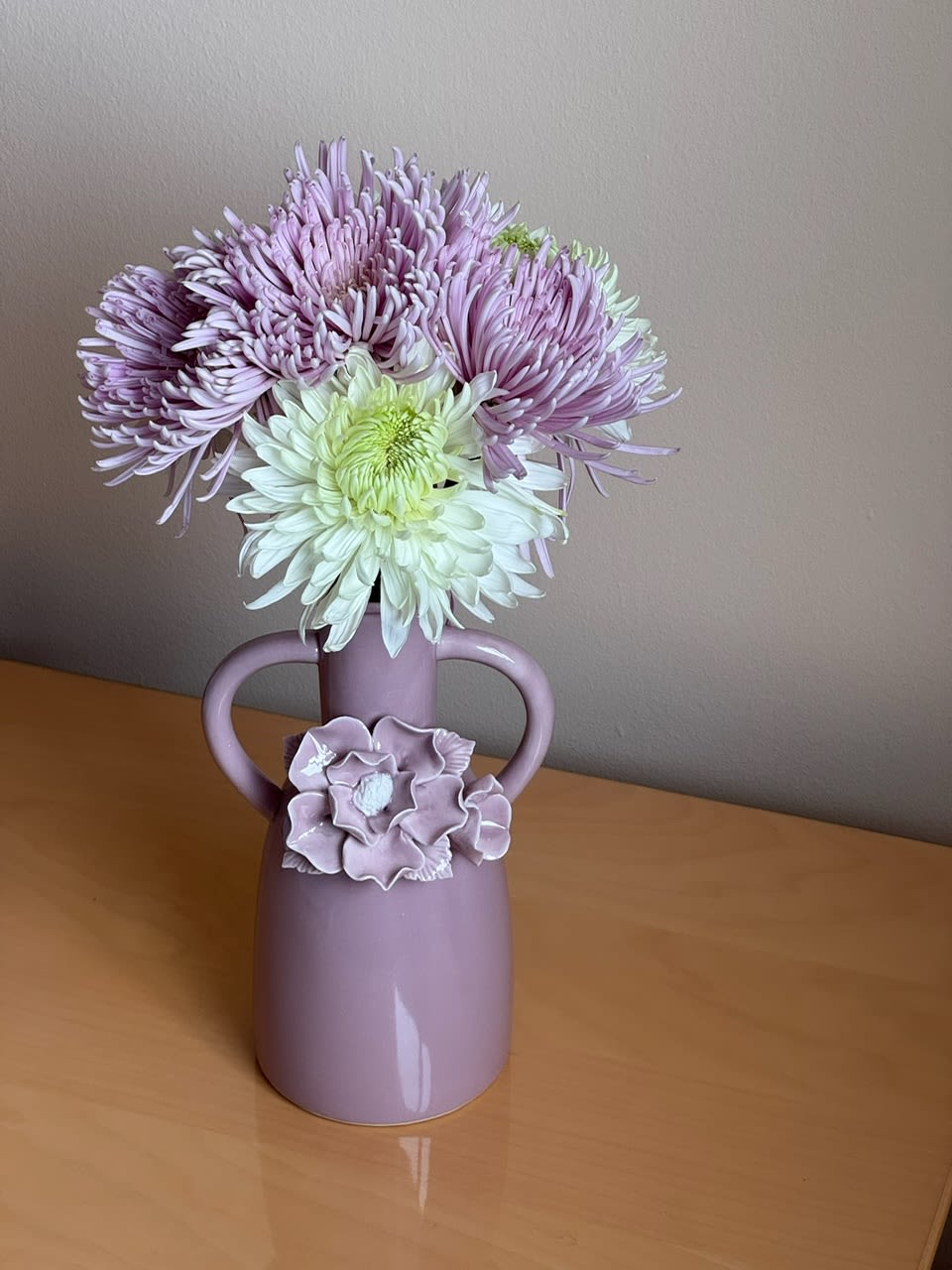 Lavender and white chrysanthemums in a pink vase with handles