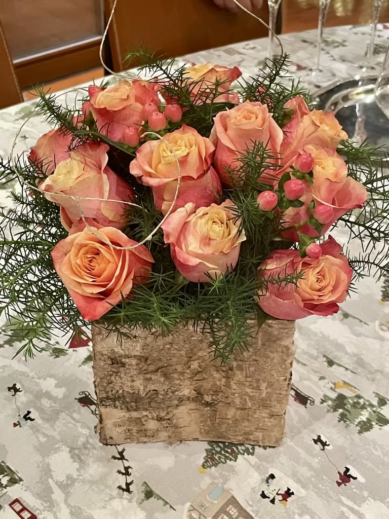 Pink and peach roses arranged in a birch bark container