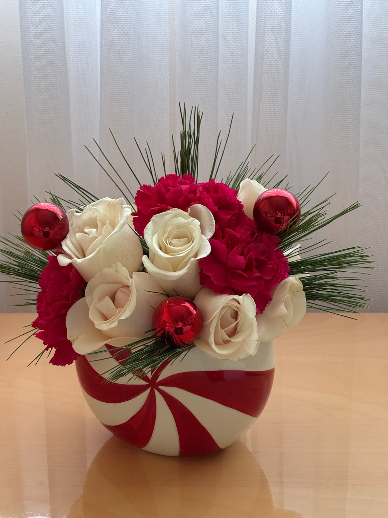 White roses and red carnations in a red-and-white vase with red ornaments