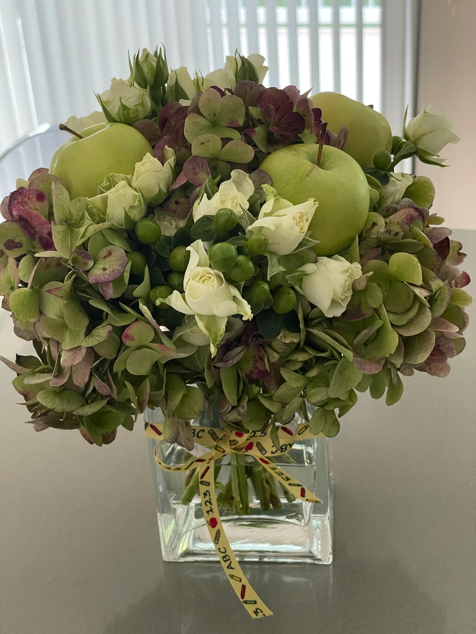 Green hydrangea and white rose arrangement in a clear square vase