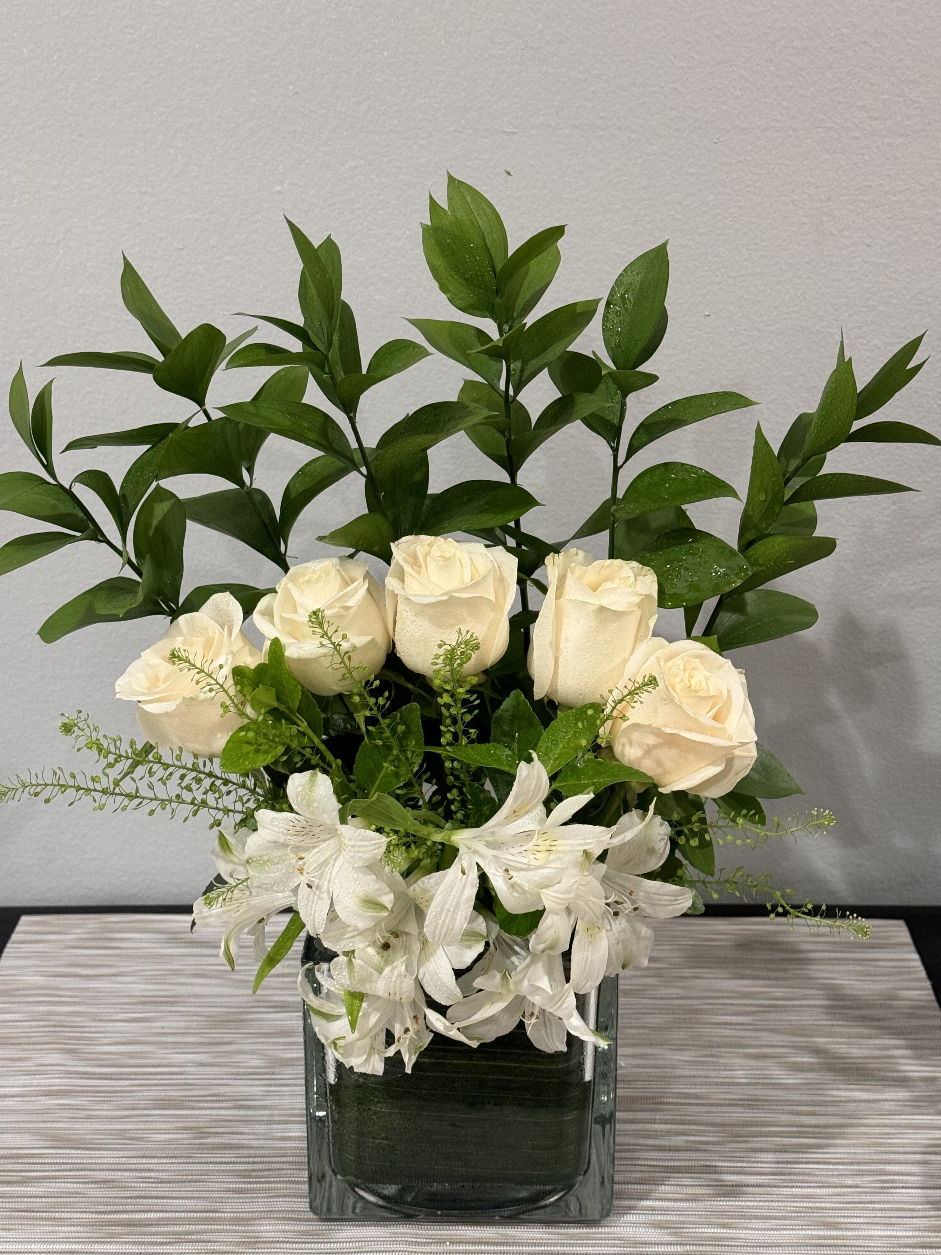 White roses and alstroemeria in a square glass vase