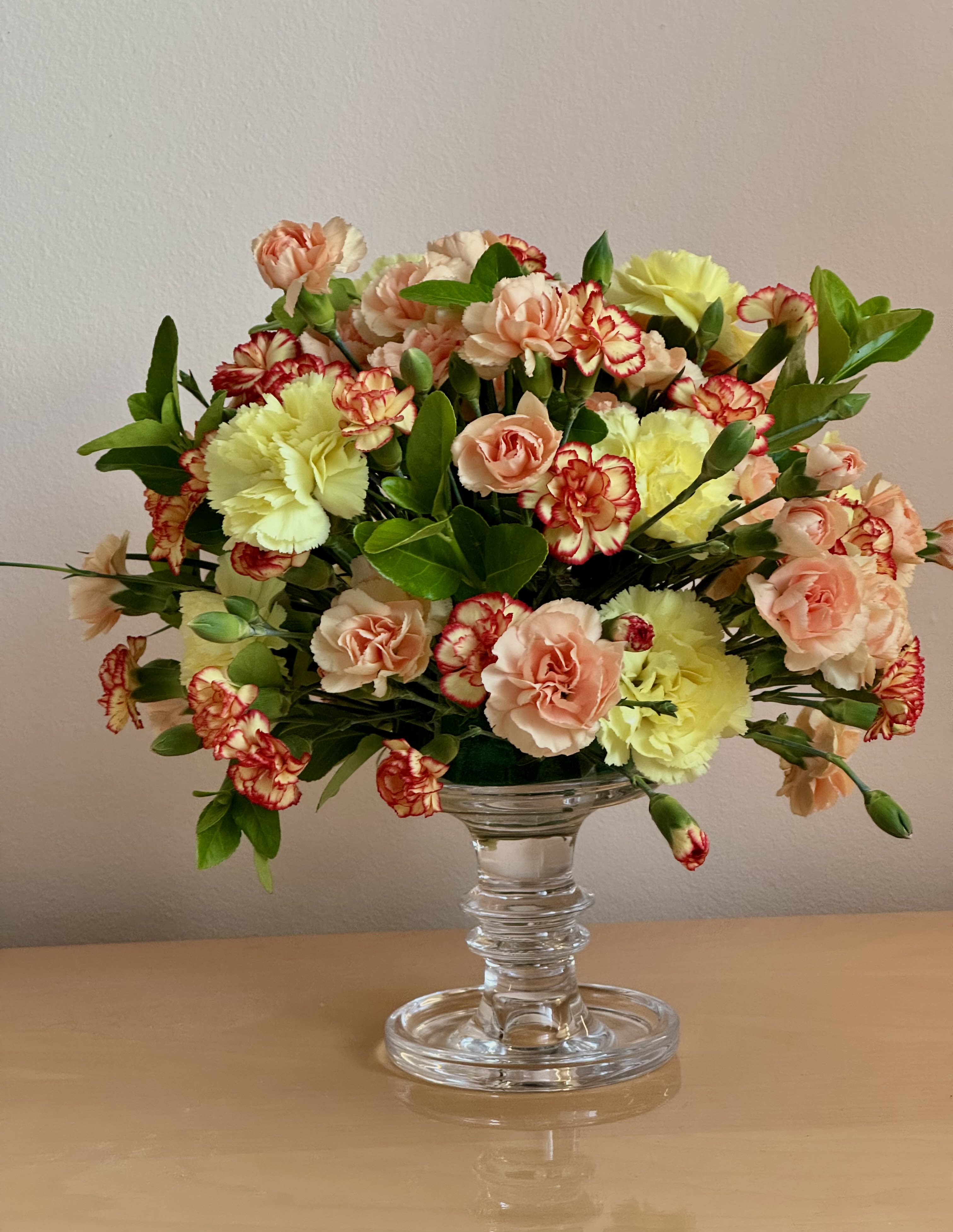 Mixed carnations and peach spray roses in a clear glass vase