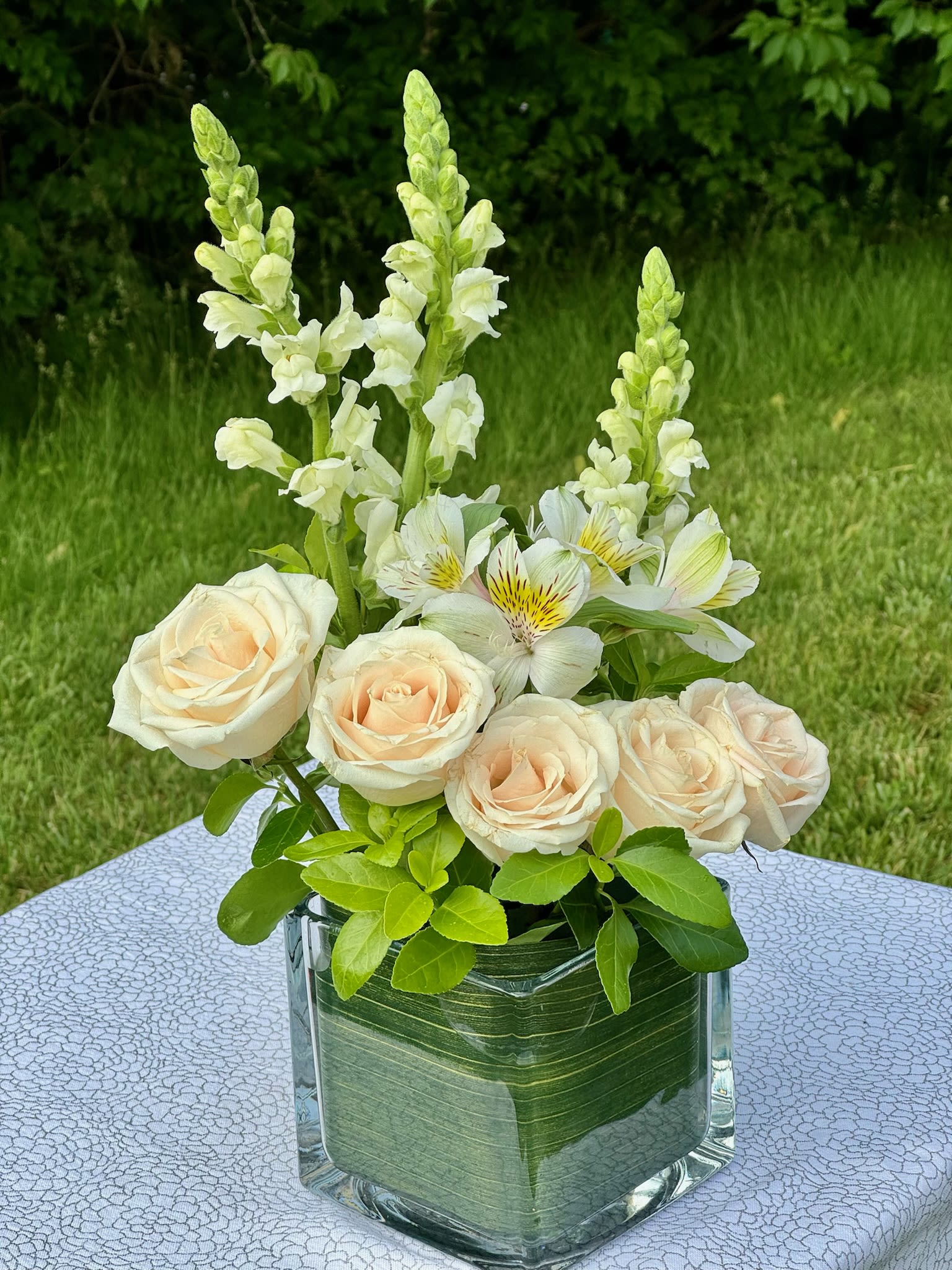 Cream roses and white snapdragons in a glass vase
