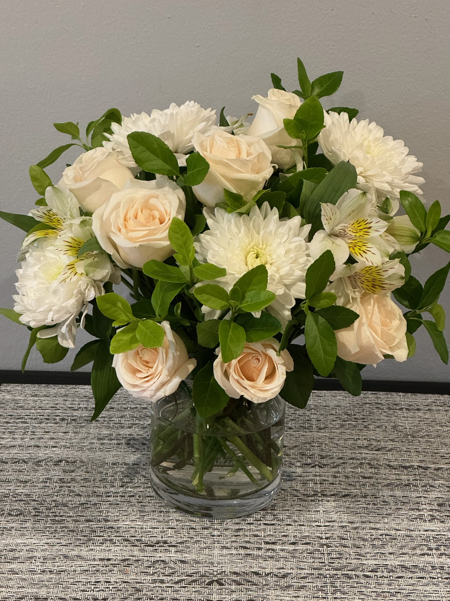 Bouquet of white roses and white chrysanthemums in a clear glass vase