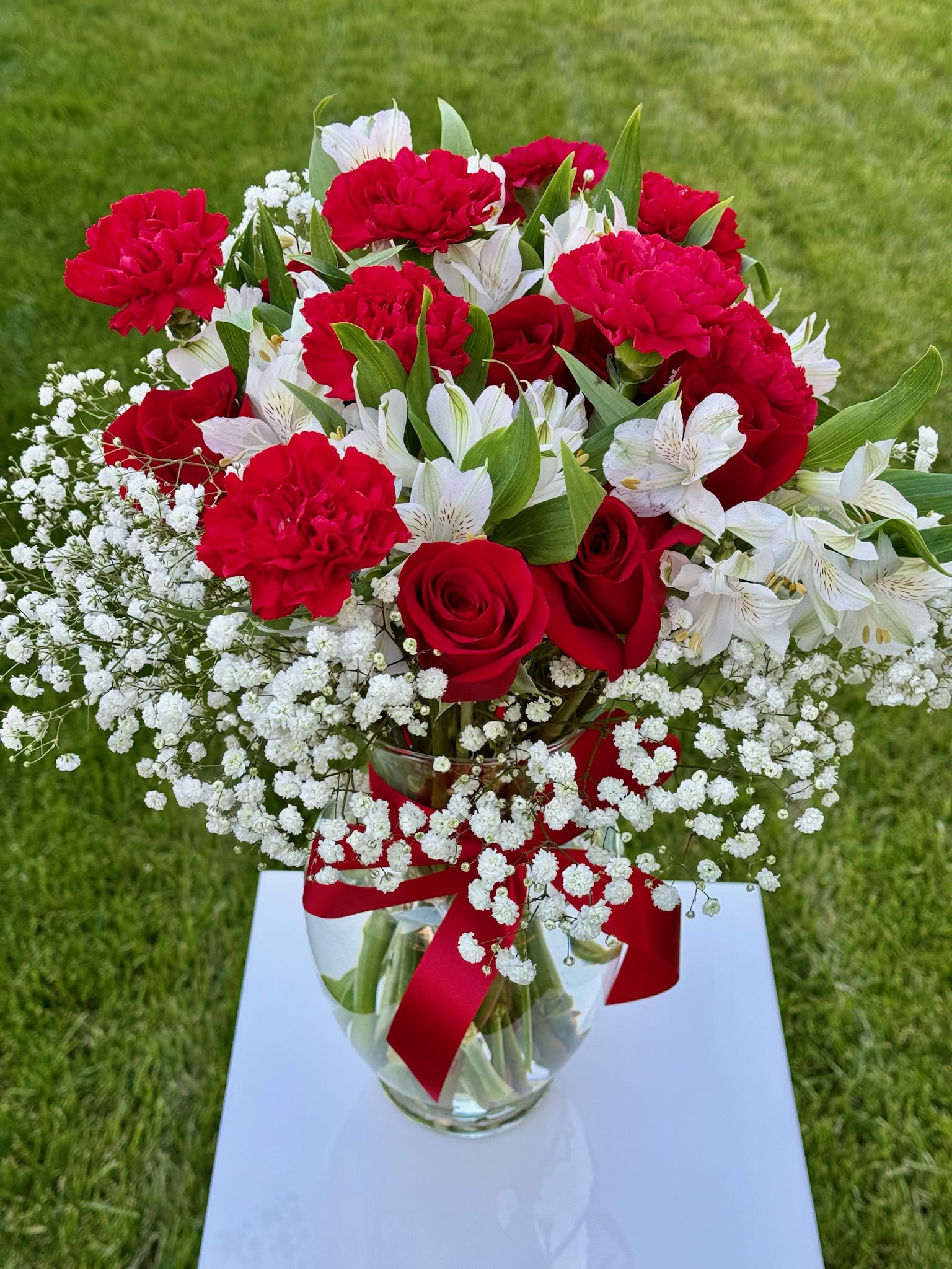 Red roses and carnations with white alstroemeria in a glass vase