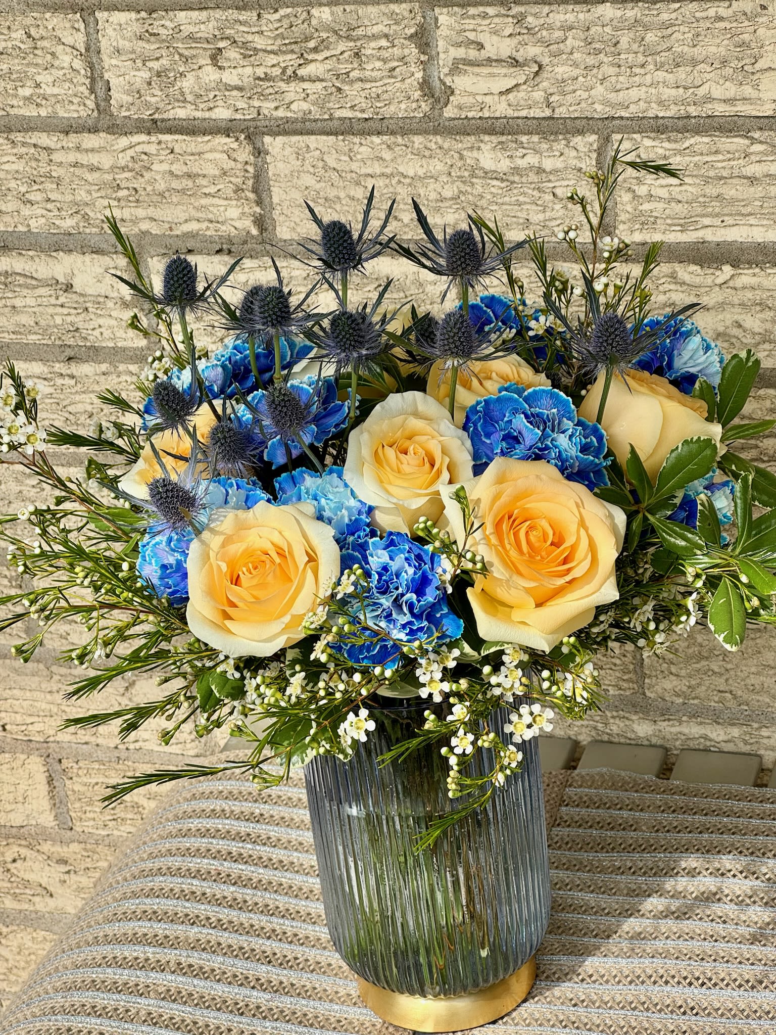 Yellow roses and blue carnations in a glass vase