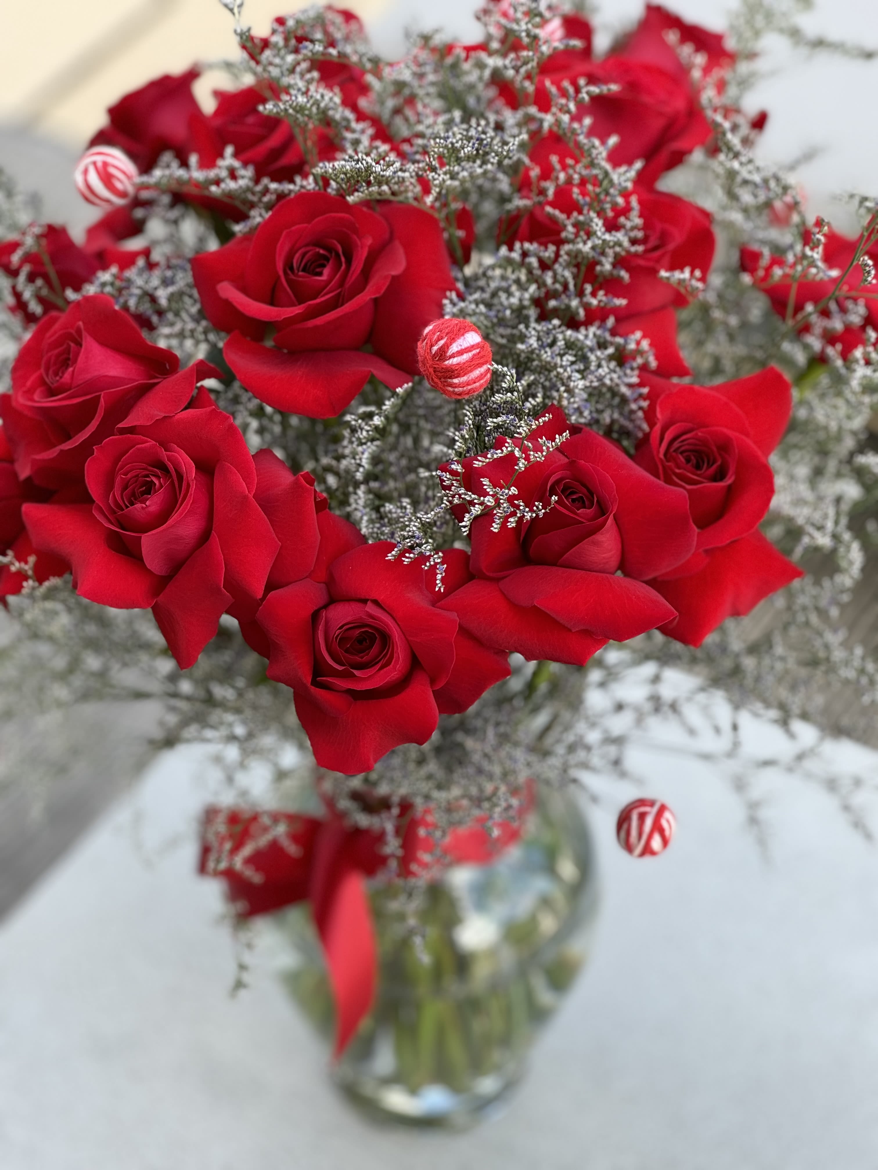 Red roses arranged in a glass vase with silver filler and ribbon