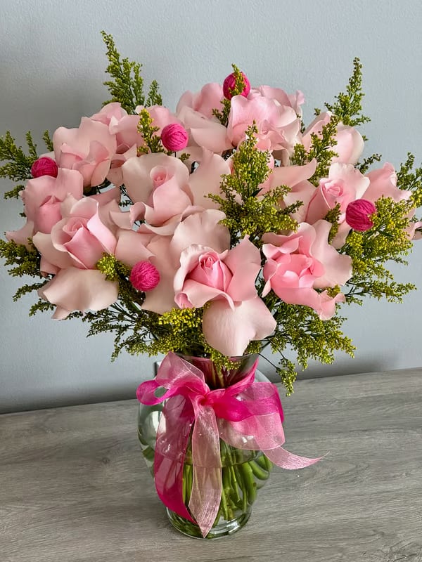 Pink rose bouquet in a glass vase with a bright ribbon