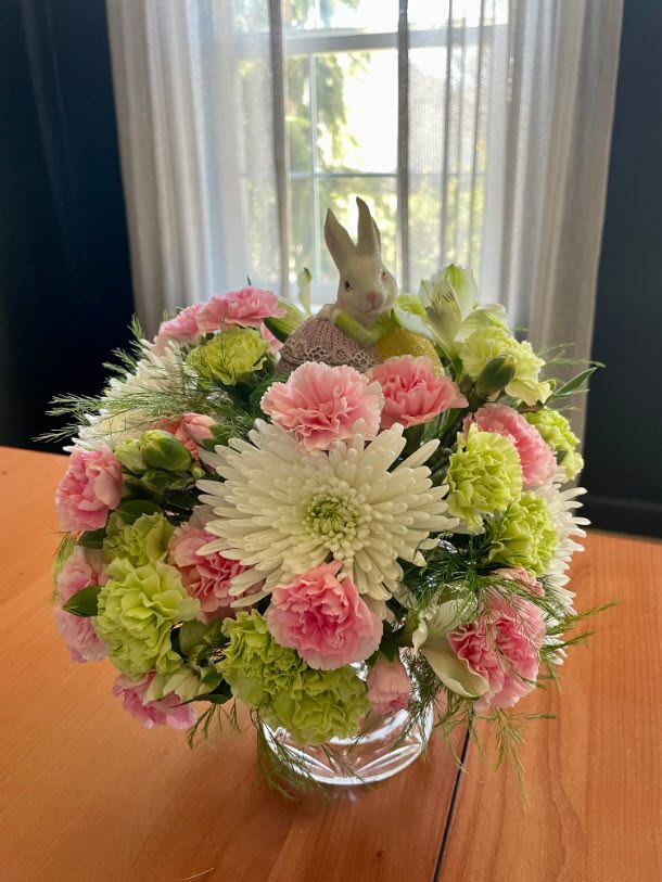 Bouquet of pink and green flowers in a glass vase with a small bunny figurine