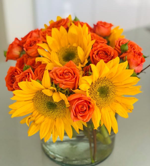 Sunflowers and orange roses in a clear glass vase
