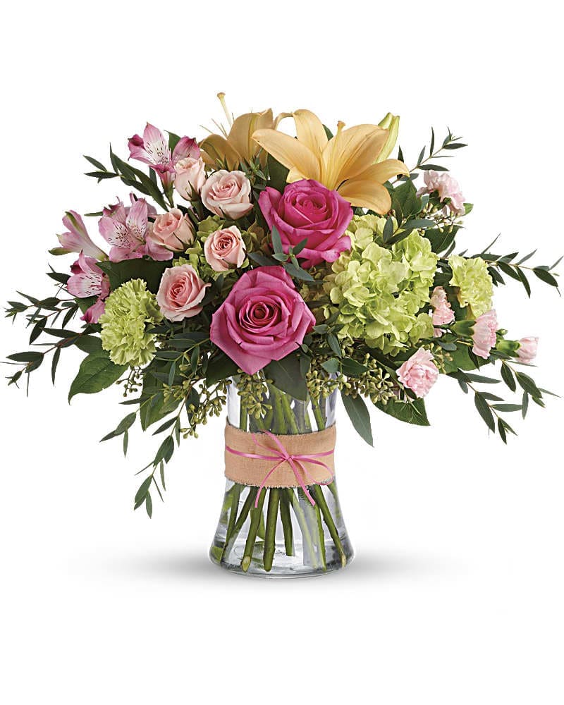 Bouquet of pink roses, lilies, and green hydrangeas in a glass vase