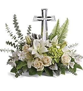 White floral arrangement with lilies, roses, and a silver cross
