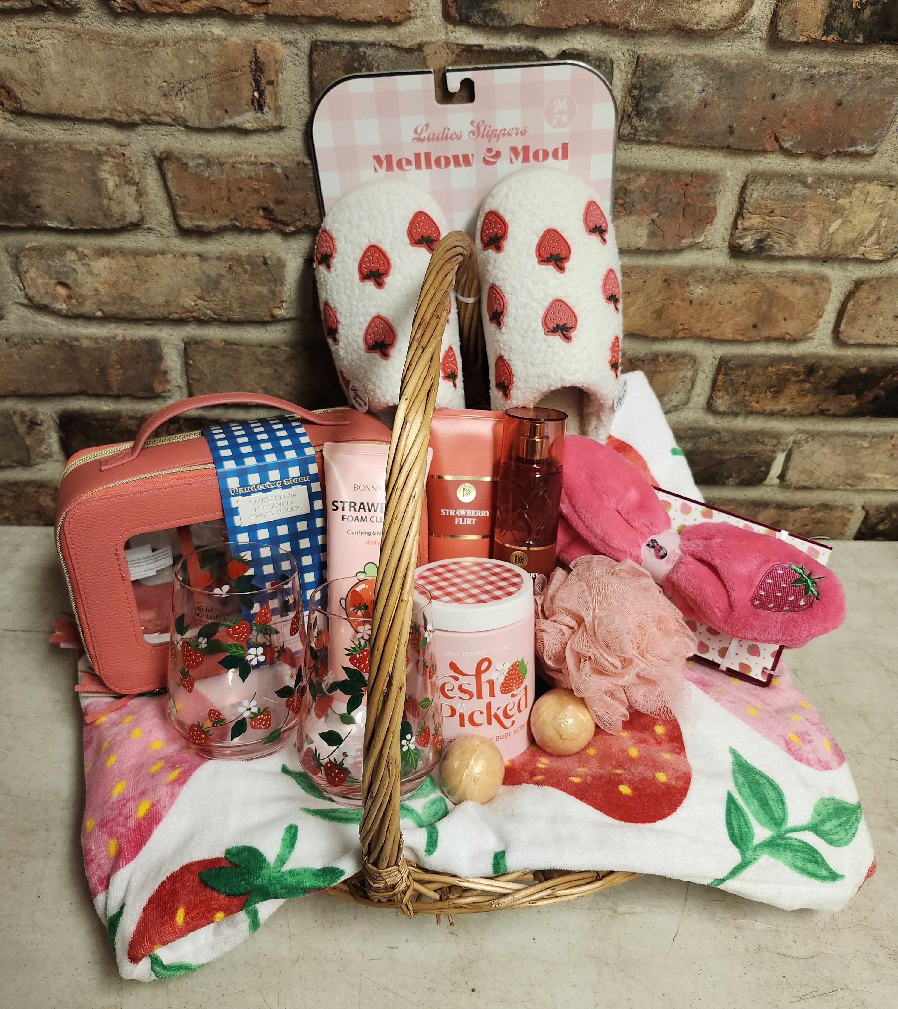 Gift basket with strawberry-themed slippers, socks, and bath items