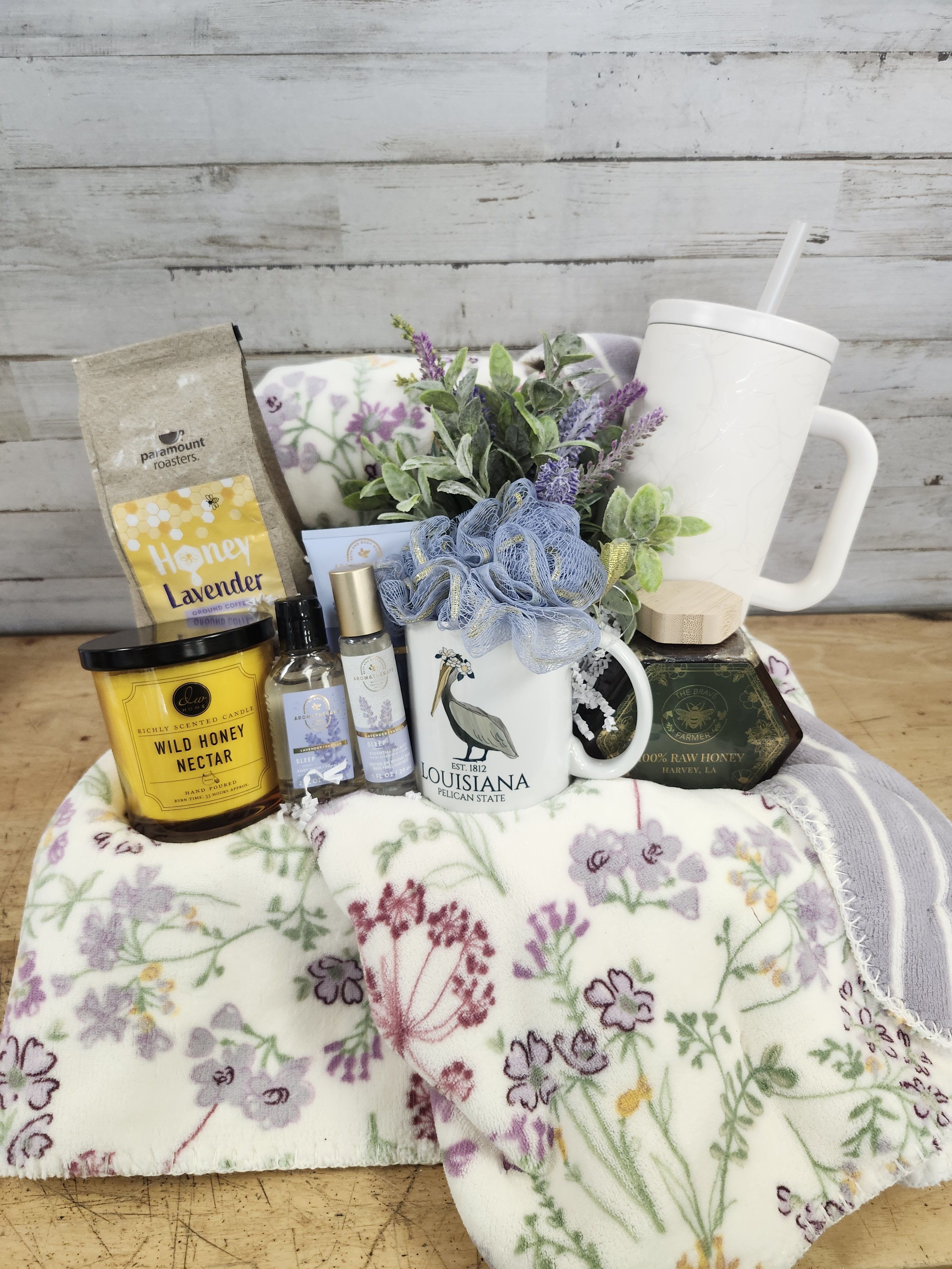 Gift basket with a floral blanket, mug, candle, honey, and lavender items