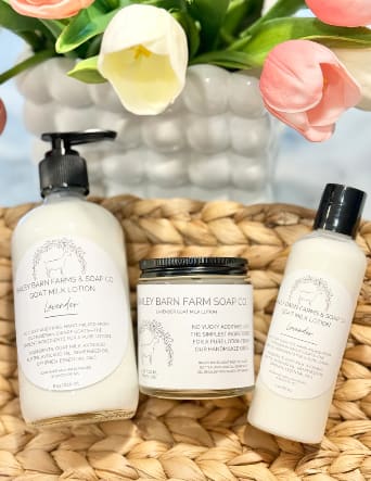 Gift set with lotion, soap, and a candle beside tulips in a woven basket