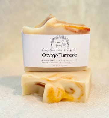 Two orange turmeric soap bars stacked on a soft surface