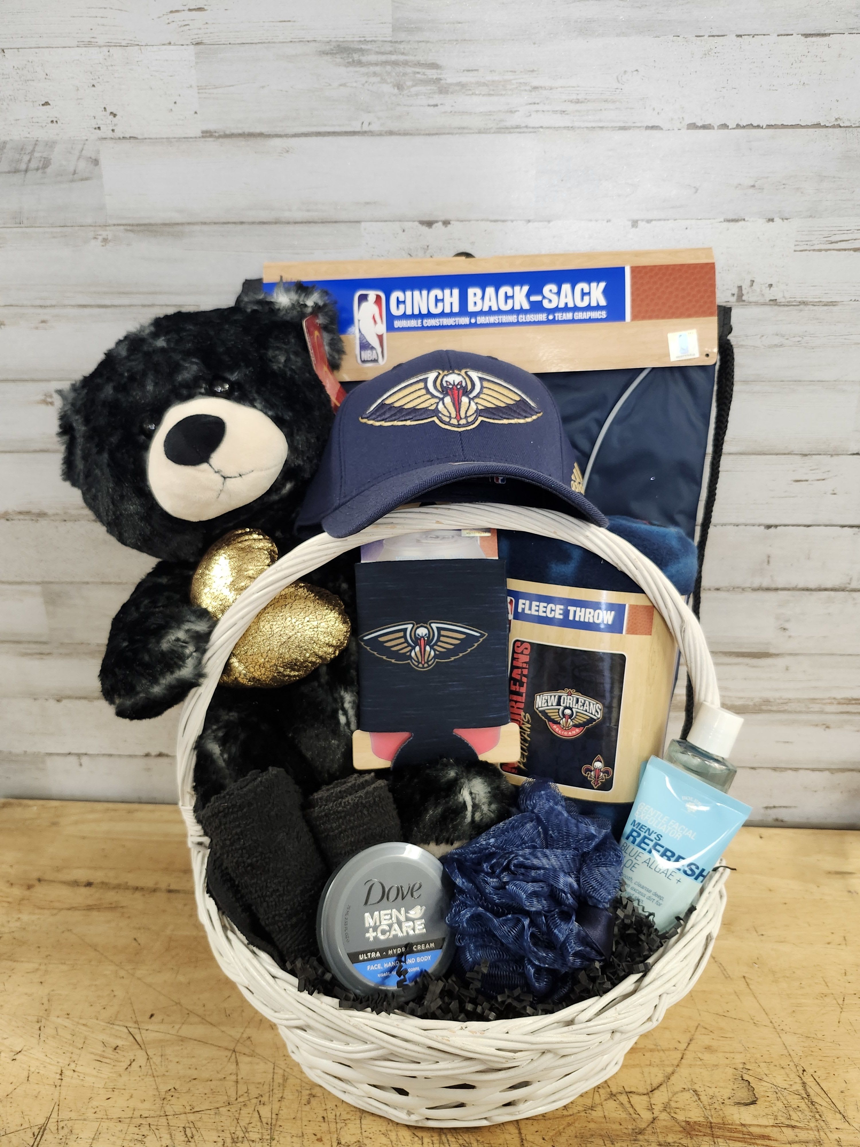 Gift basket with a teddy bear, sports items, and grooming products