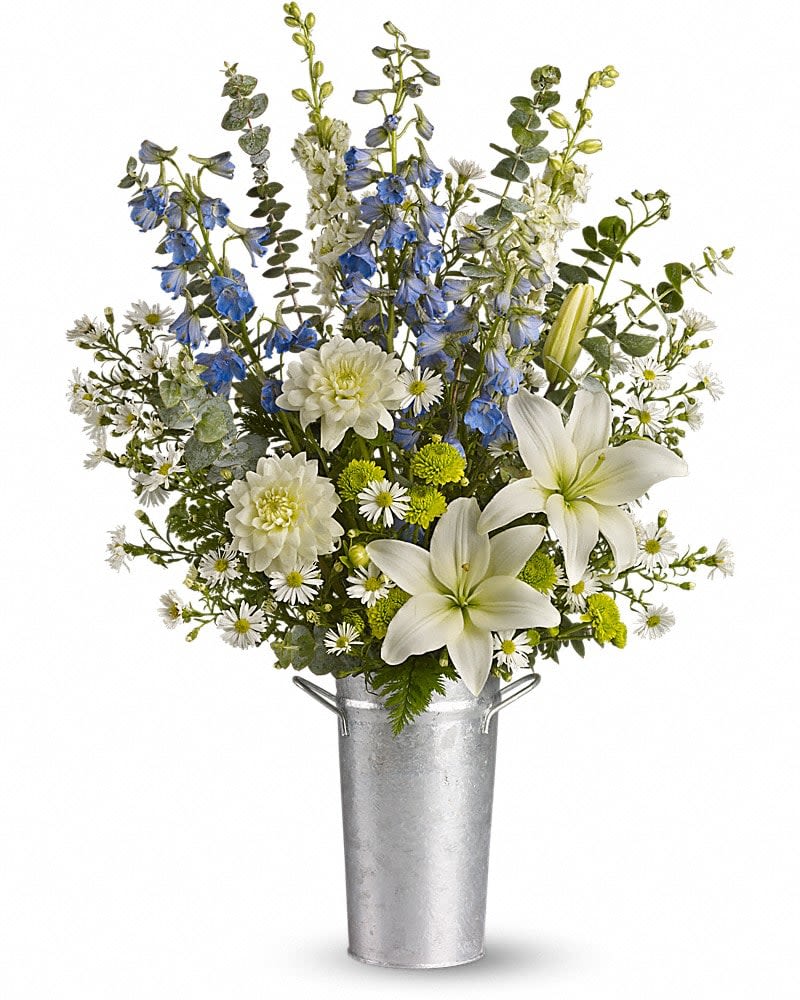 White lilies and blue delphinium in a silver bucket vase