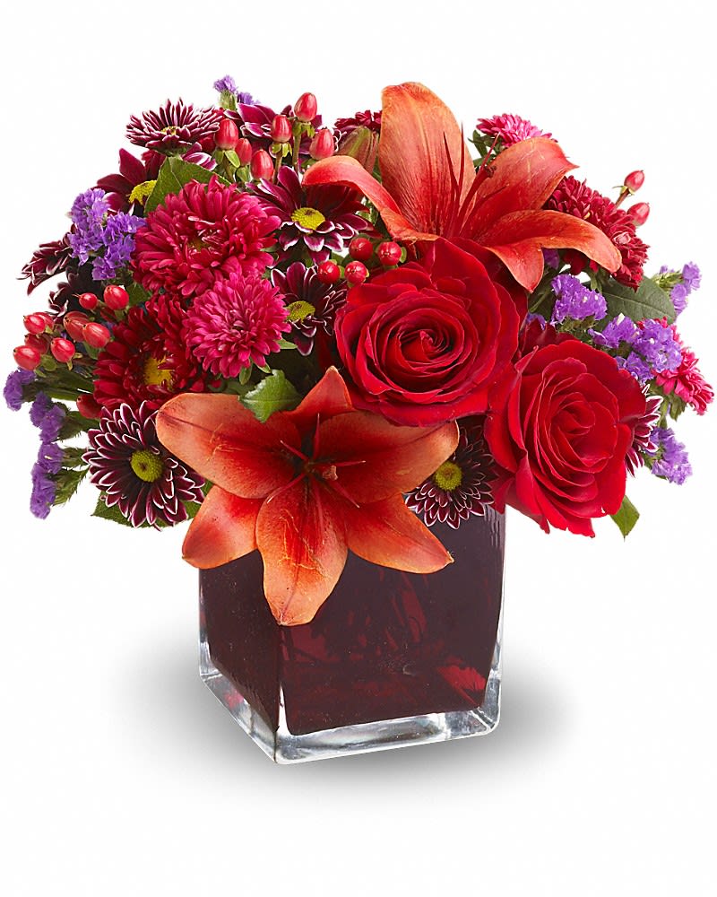 Red and orange floral arrangement in a square glass vase