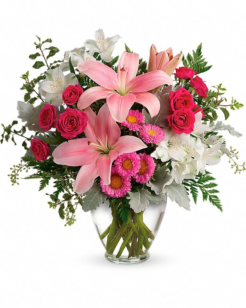 Pink lilies and roses arranged in a clear glass vase