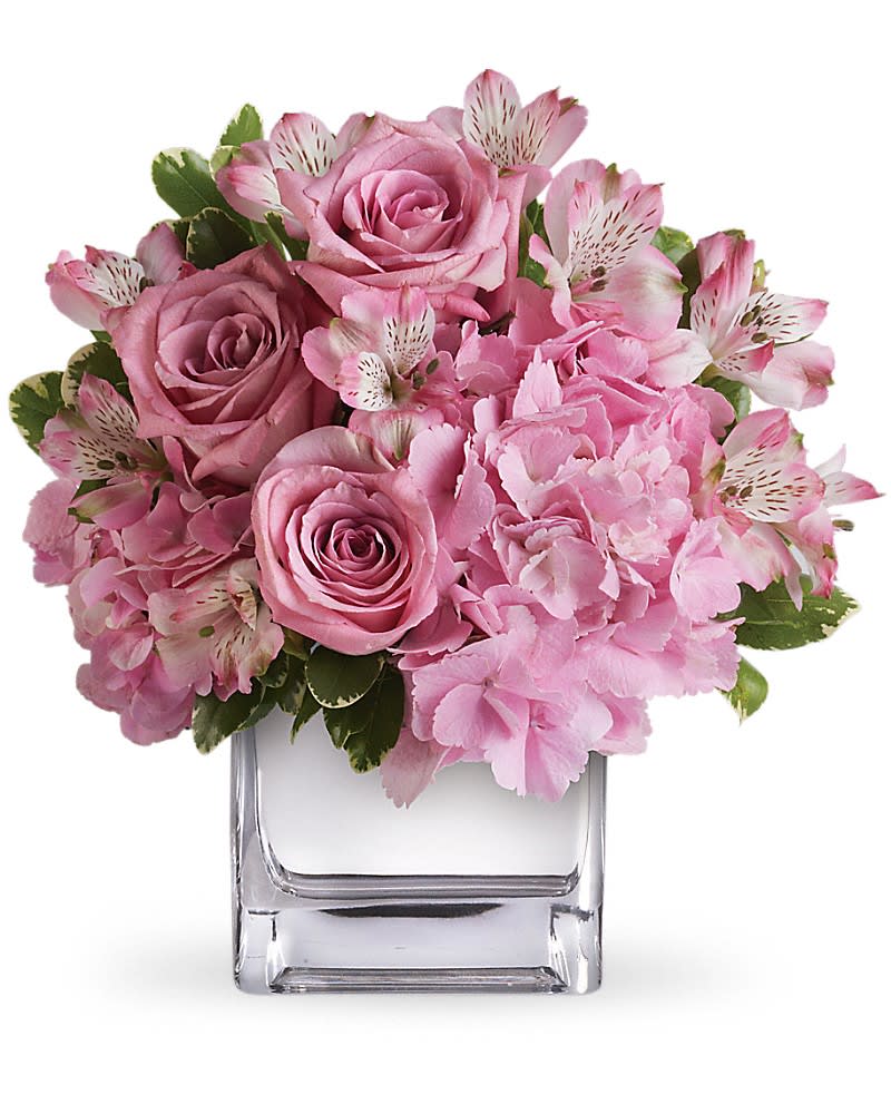 Pink roses and hydrangeas arranged in a clear square vase