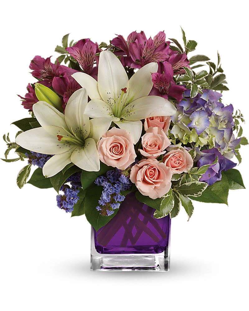 Bouquet of white lilies, pink roses, and purple flowers in a purple vase