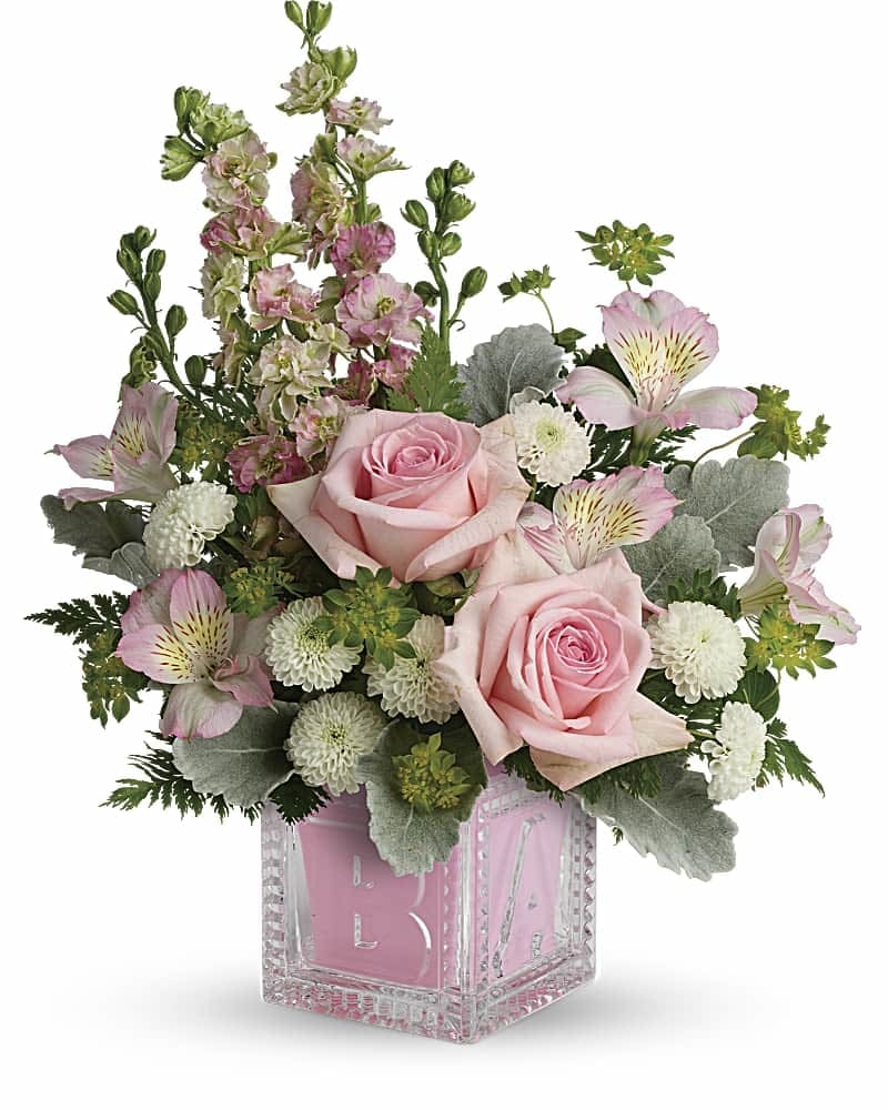 Pink roses and mixed blooms arranged in a clear pink glass vase