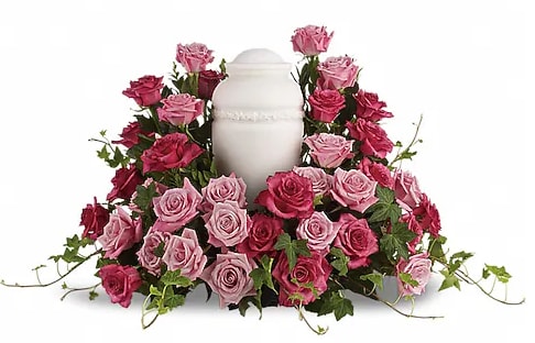 Pink and red roses arranged around a white urn