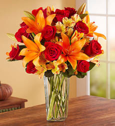 Bouquet of red roses and orange lilies in a clear glass vase