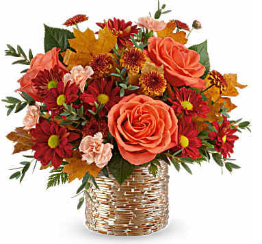 Bouquet of orange roses and red daisies in a woven basket