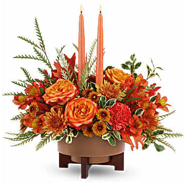 Orange floral centerpiece with two tall taper candles in a low bowl