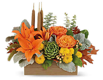 Orange lilies and roses in a wooden box with candles