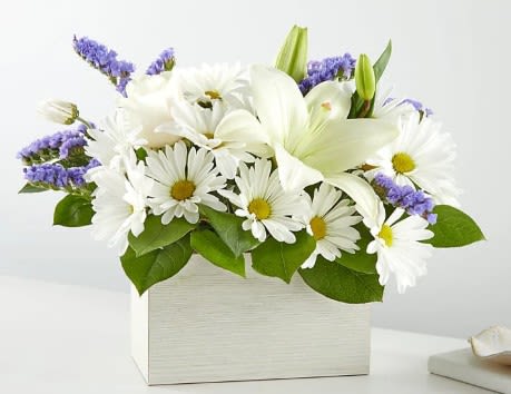 White lilies and daisies in a white box with purple accents