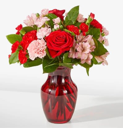 Red roses and pink carnations in a red glass vase