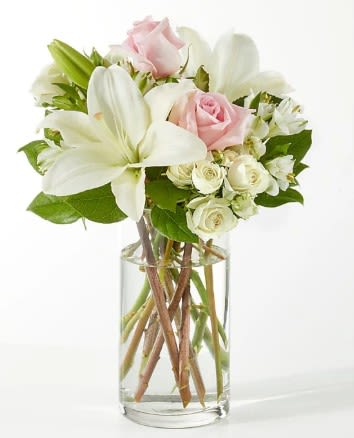 Clear glass vase with white lilies and pale pink and white roses.