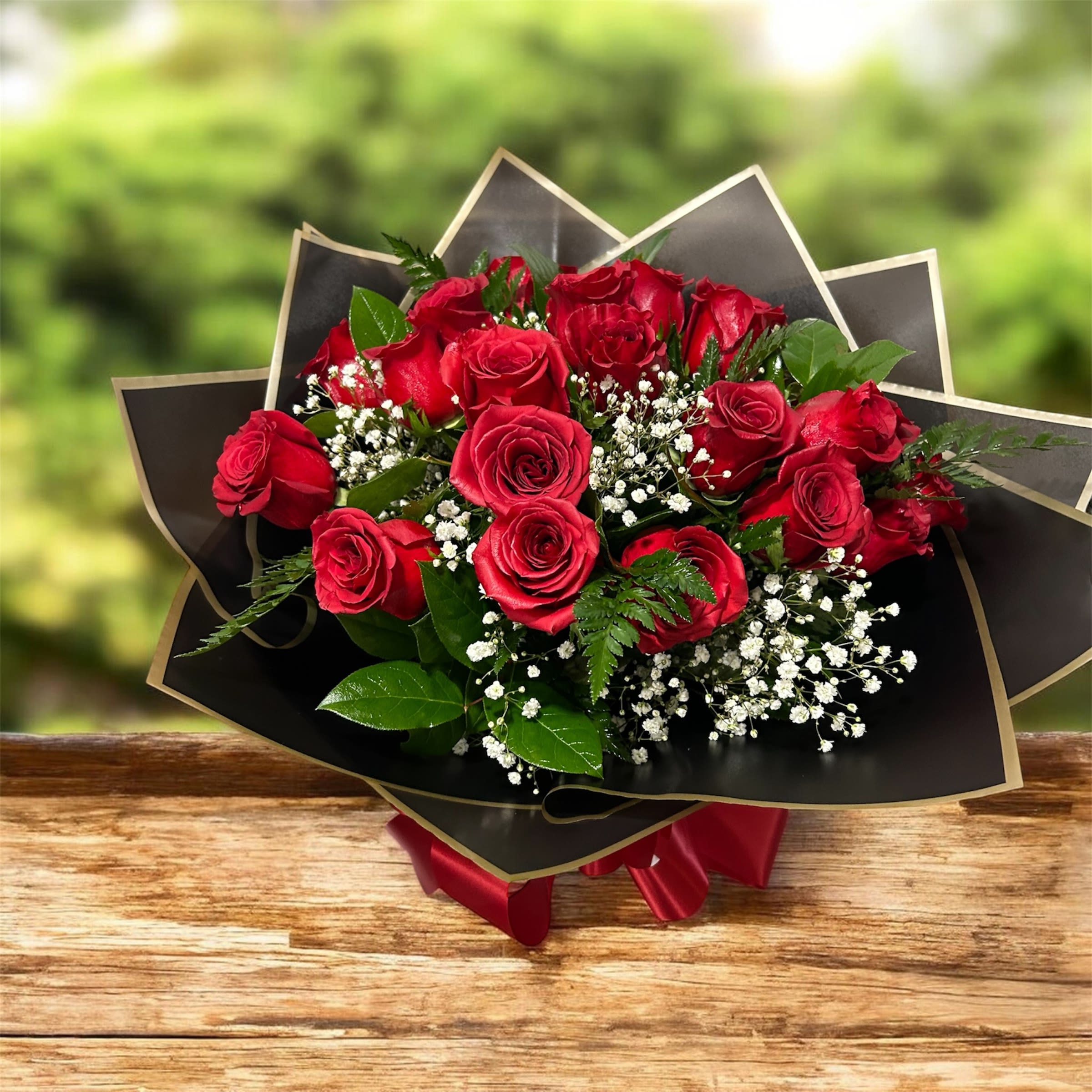 25 Reasons I Love You - Make a bold statement with our 25 Reasons I Love You bouquet. This stunning hand-wrapped arrangement features two dozen premium long-stem red roses, beautifully accented with delicate baby’s breath and lush greenery.  Wrapped in elegant black and gold trim paper and finished with a rich red satin ribbon, this bouquet is designed to impress from the very first glance. Each rose symbolizes love, passion, and admiration — making it the perfect gift for anniversaries, Valentine’s Day, birthdays, or simply to say “I love you.”  A timeless classic that never goes out of style.