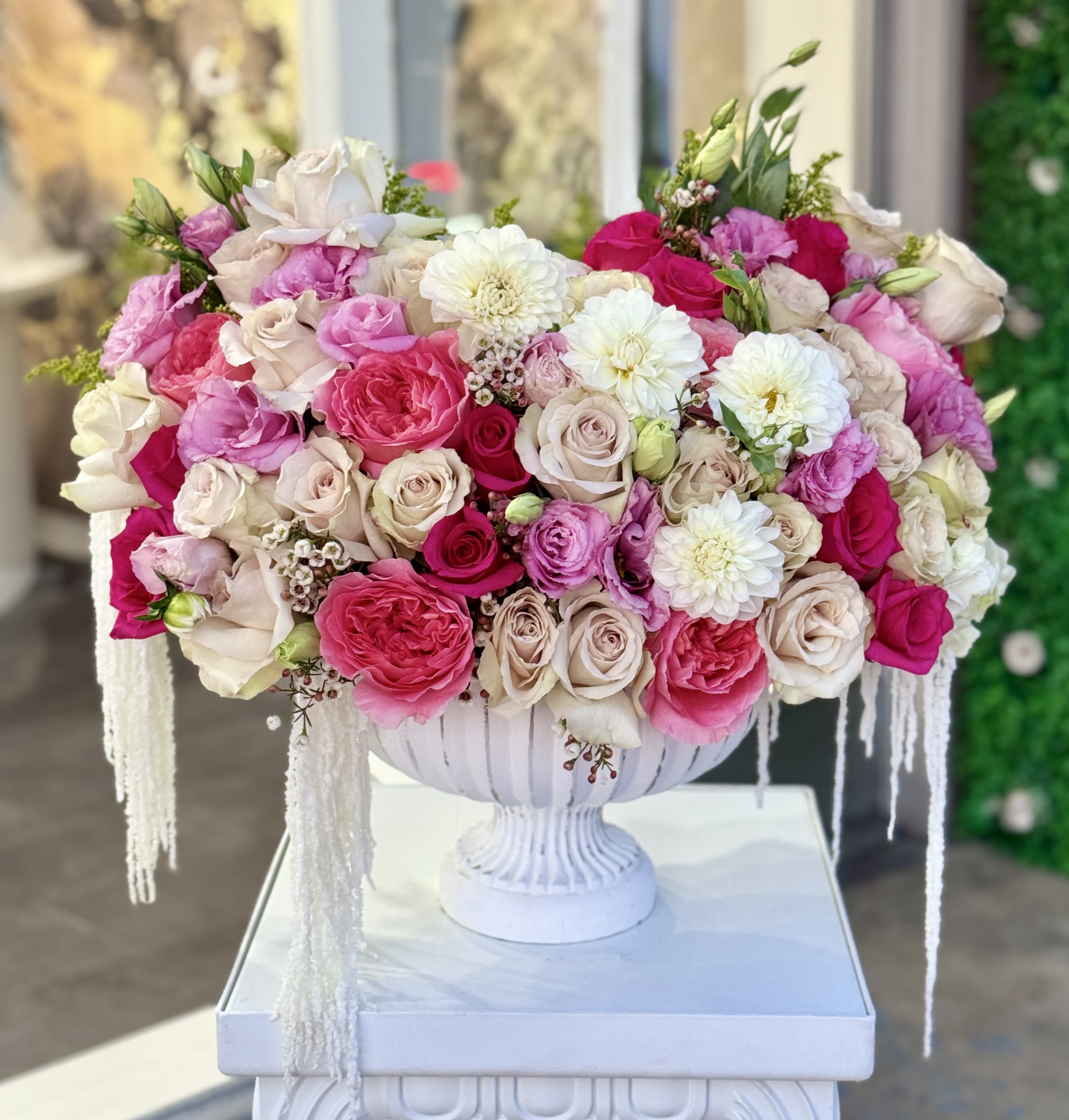 Large pink and white rose arrangement in a white pedestal vase