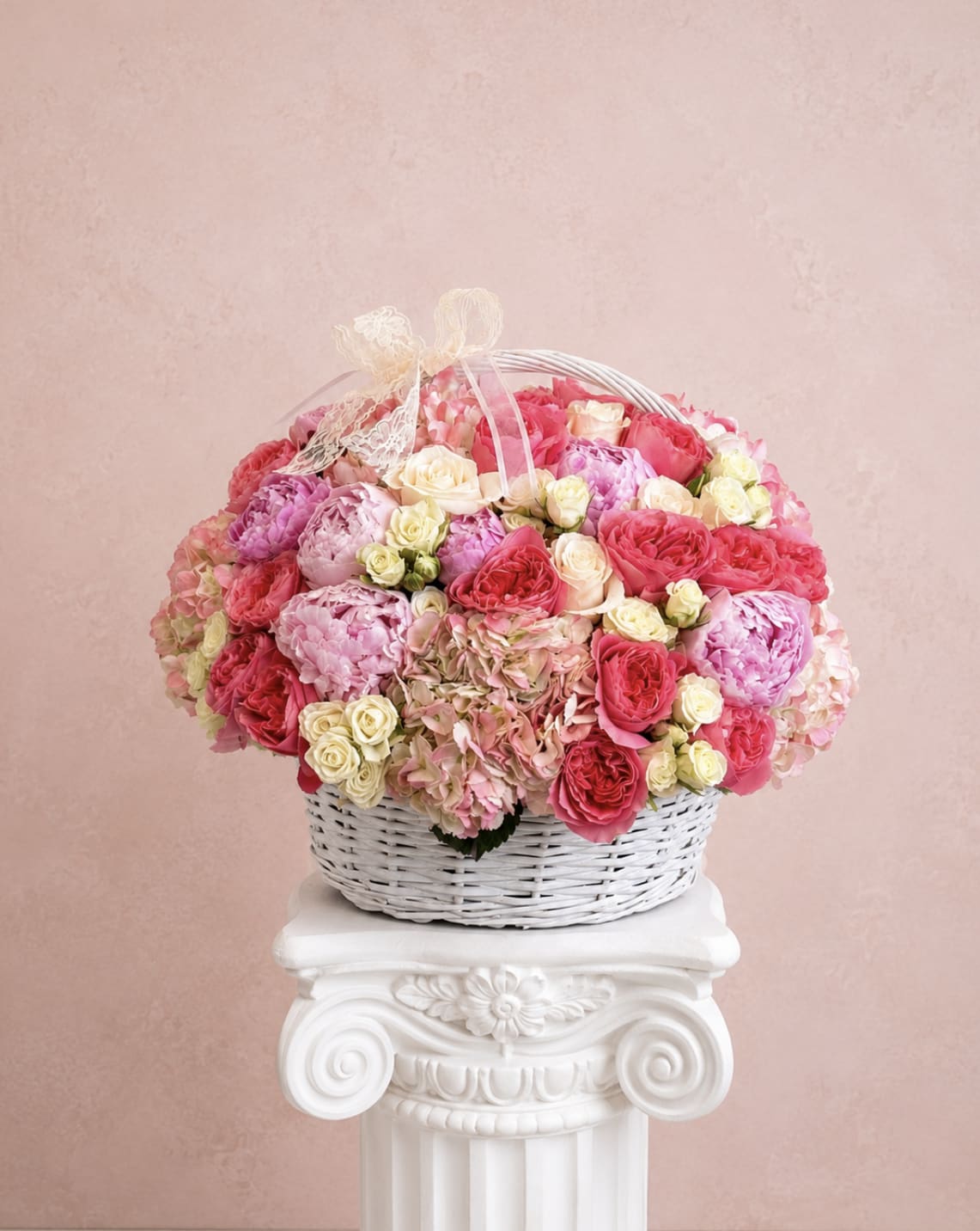 Basket of pink and cream roses with hydrangeas and a ribbon bow