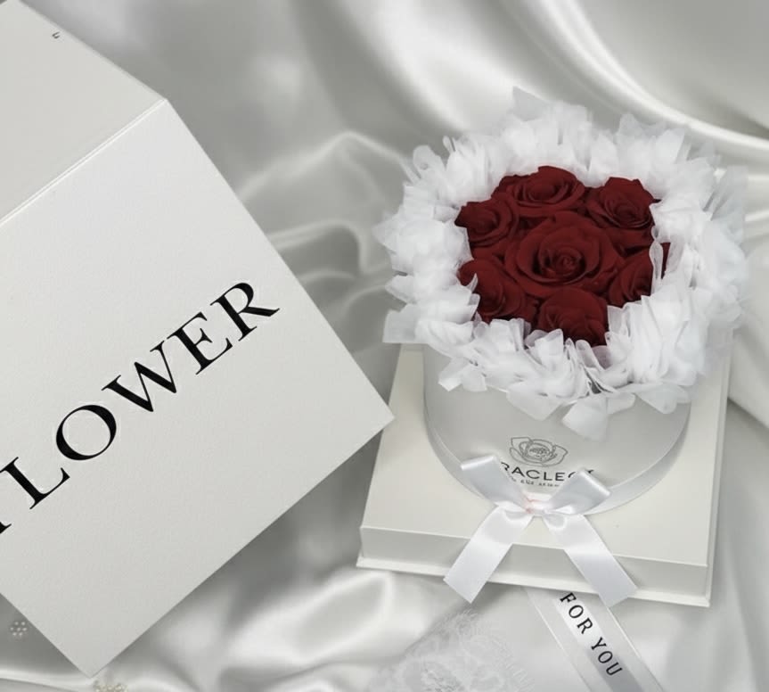 Eternal Red Elegance – White Luxury Box - A refined expression of love and timeless beauty.  Our Eternal Red Elegance features premium preserved red roses carefully arranged inside a sophisticated white round luxury box with satin ribbon detailing. The contrast between the crisp white presentation and the deep red roses creates a clean, elegant, and romantic statement.  Preserved roses maintain their natural beauty for months — even years — with proper care, making this arrangement a meaningful and lasting keepsake.  Perfect for romantic gestures, anniversaries, birthdays, or when you want to express love in a refined and elegant way.  A delicate yet impactful gift designed to impress.