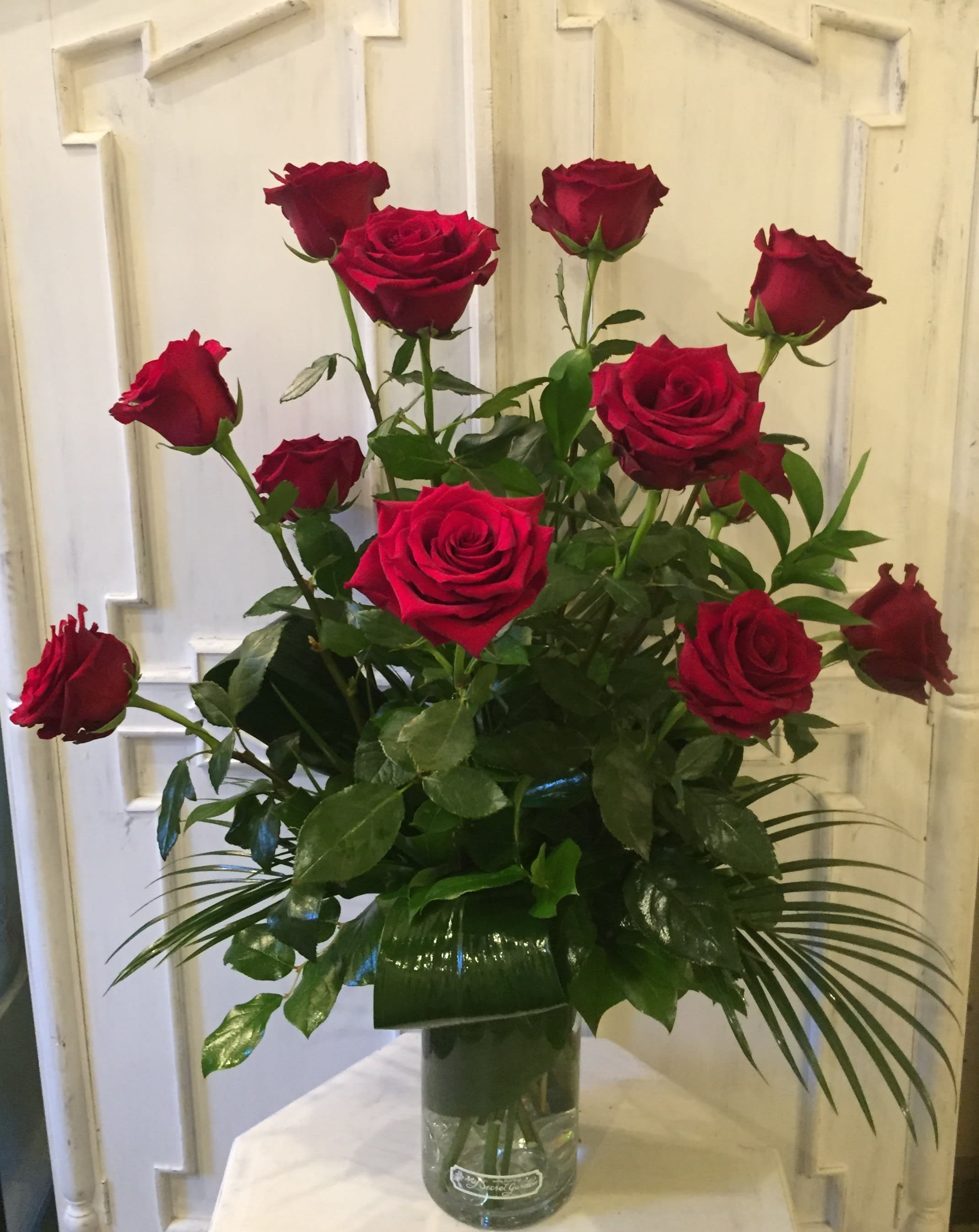 Red roses arranged in a clear glass vase with greenery